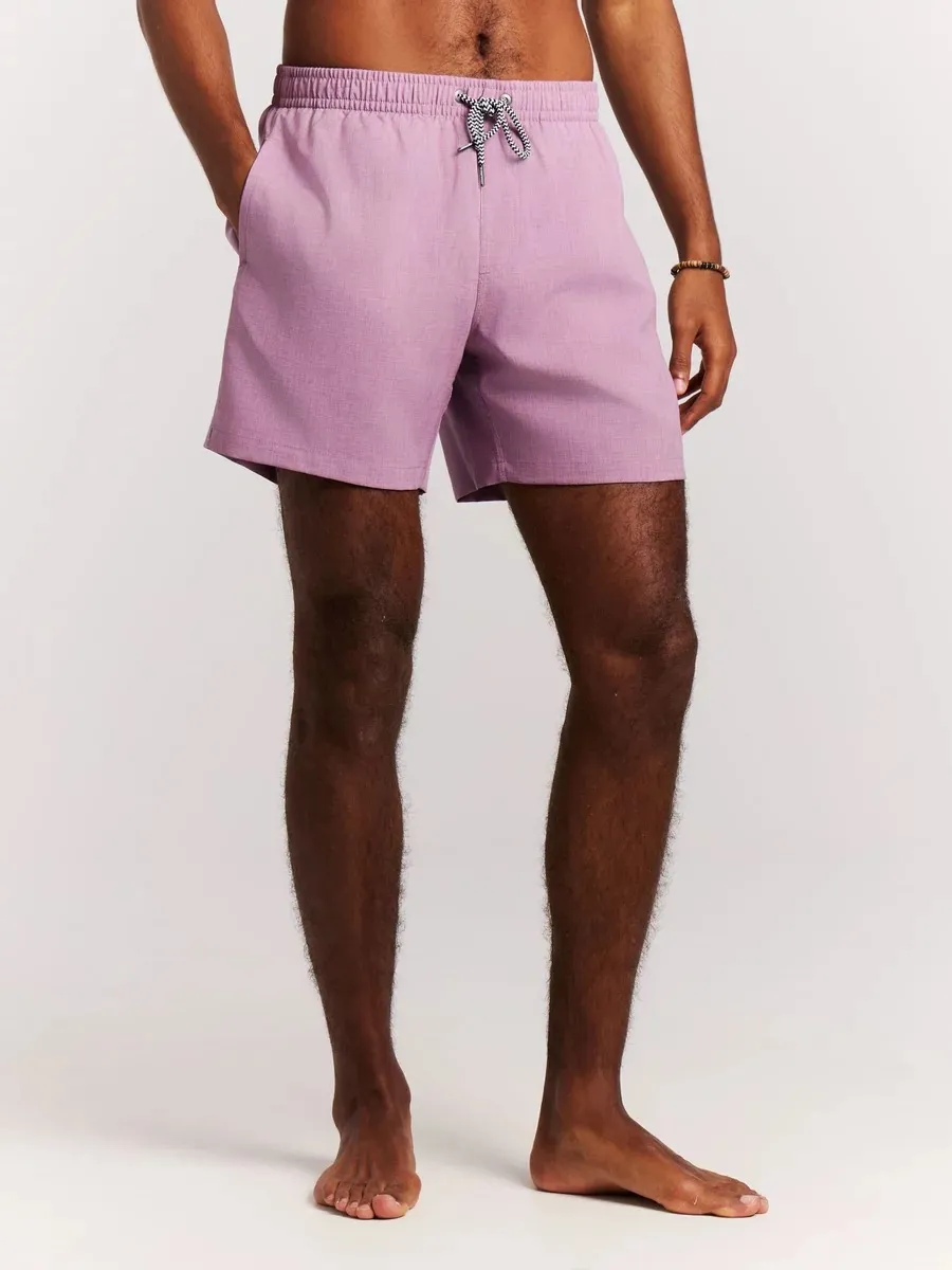A man with tanned skin wears mauve Protest Daviey beach shorts with drawstring.