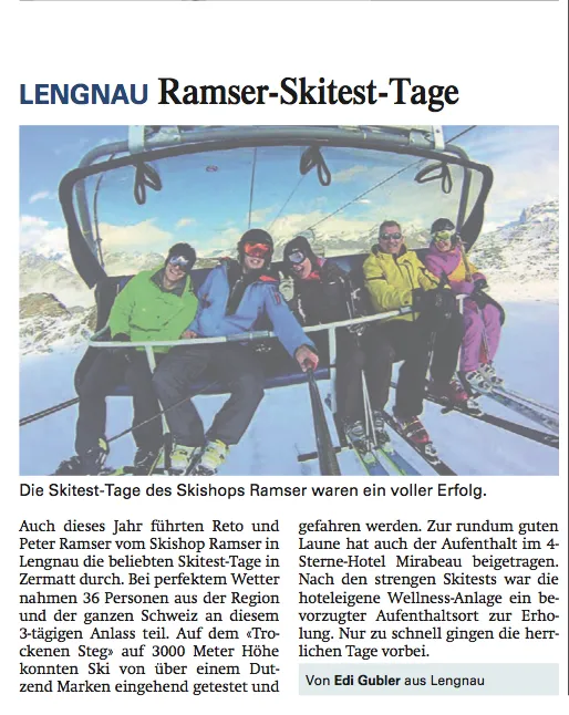 Gruppo di cinque persone sugli sci in una seggiovia di fronte a montagne innevate.