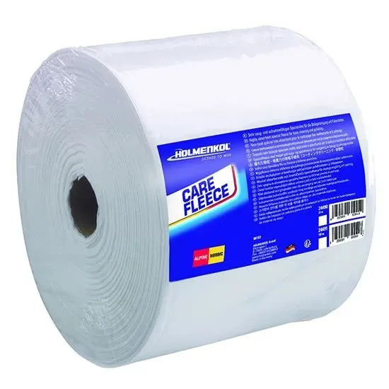 Grand rouleau de Care Fleece Holmenkol, enveloppé de blanc, pour l'entretien des skis et snowboards, posé en biais. Noyau creux visible à gauche. Étiquette bleue « Holmenkol » et « CARE FLEECE » + mode d'emploi multilingue.