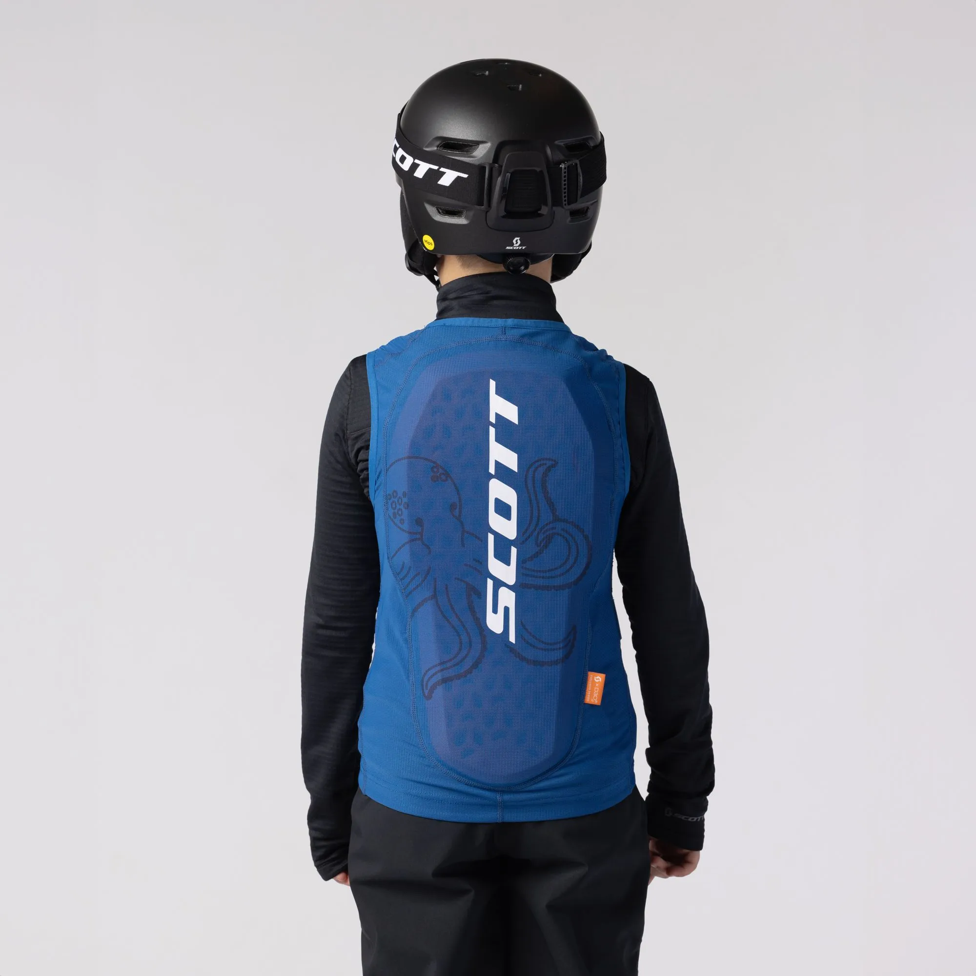 Rückenansicht eines Kindes mit Helm und blauer SCOTT Airflow Junior-Weste mit Oktopus Grafik.