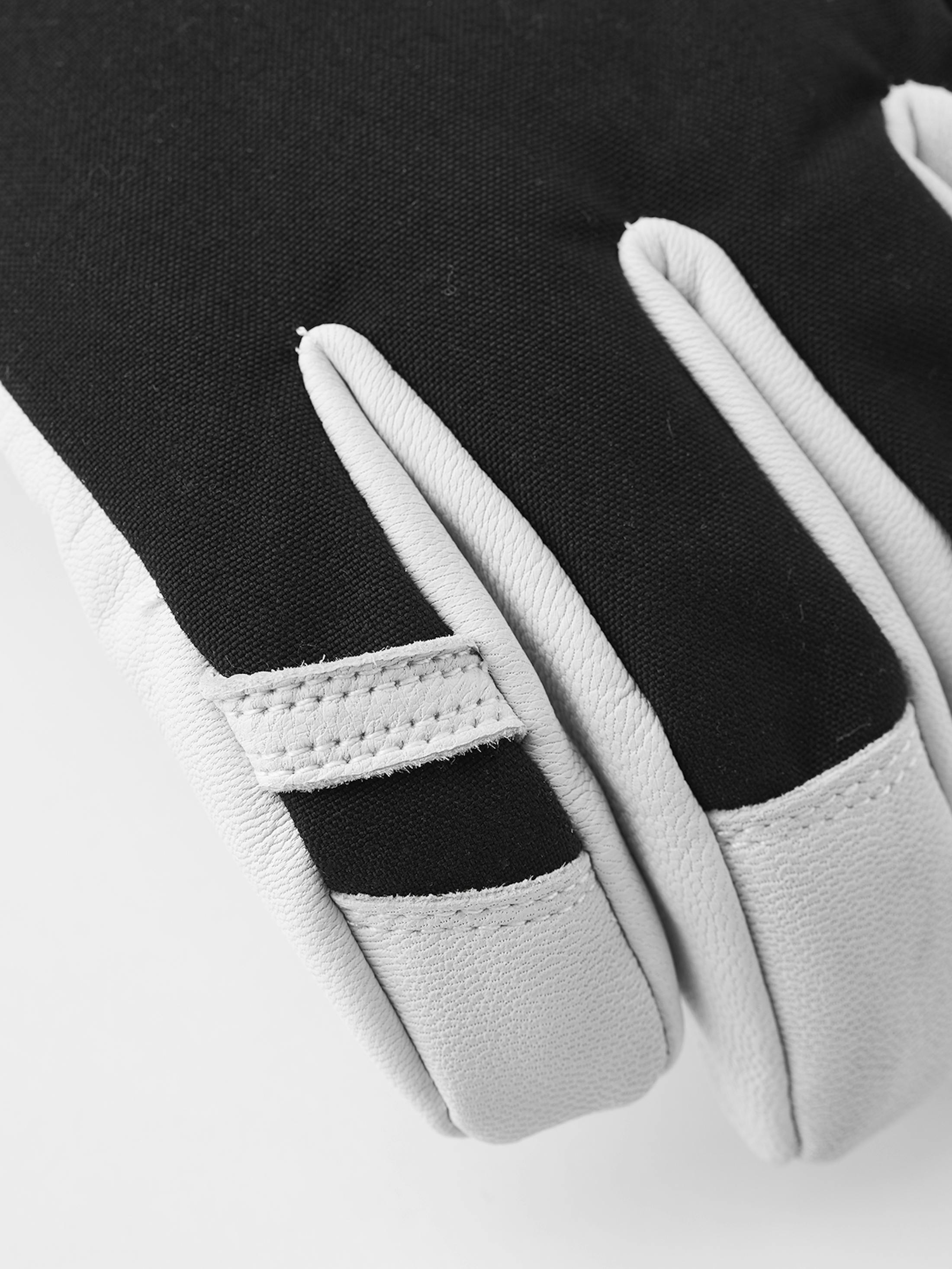 Detailaufnahme eines schwarzen/grauen Hestra Army Leather Heli Ski Mitt Handschuhs. Die Finger sind hellgrau und der Handrücken ist schwarz.