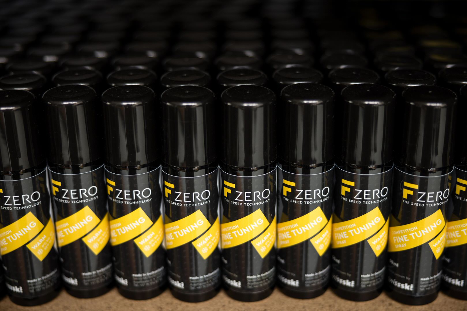 De nombreuses boîtes de spray FZero noires sont disposées en rangées serrées. Une étiquette jaune est apposée sur chaque boîte.