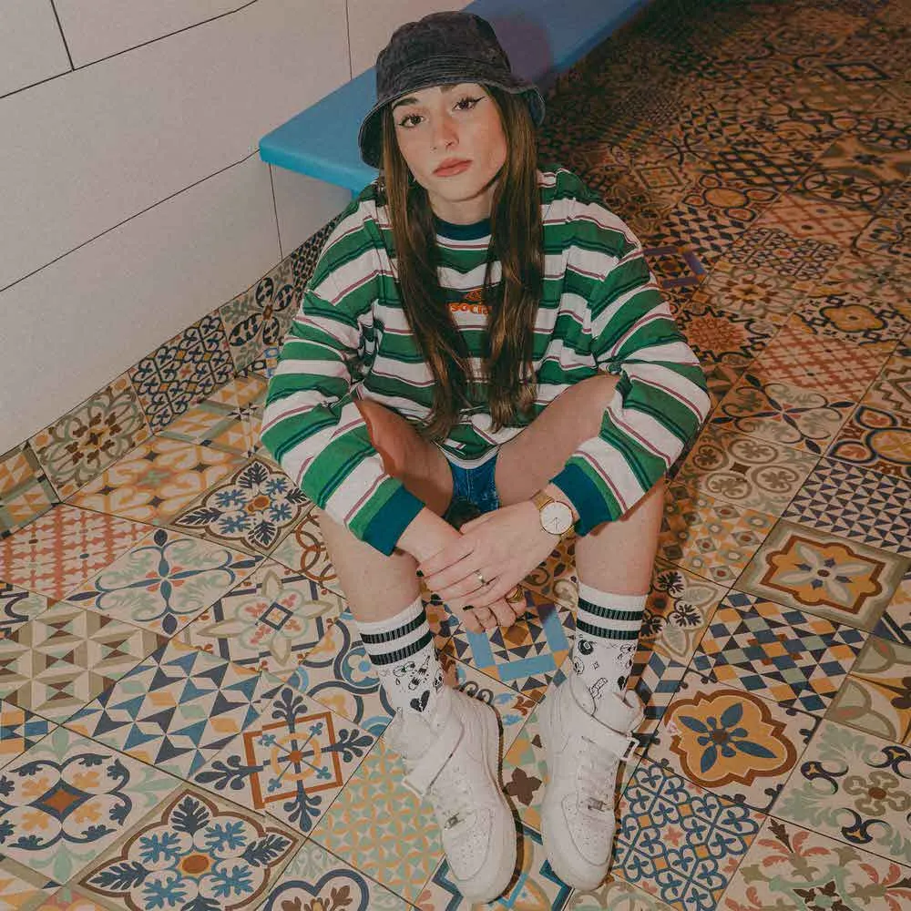 Person with flash tattoo socks sitting on patterned floor, looking into the camera.