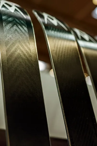 Three black skis standing next to each other with silver patterns on the top and a smooth, shiny surface.