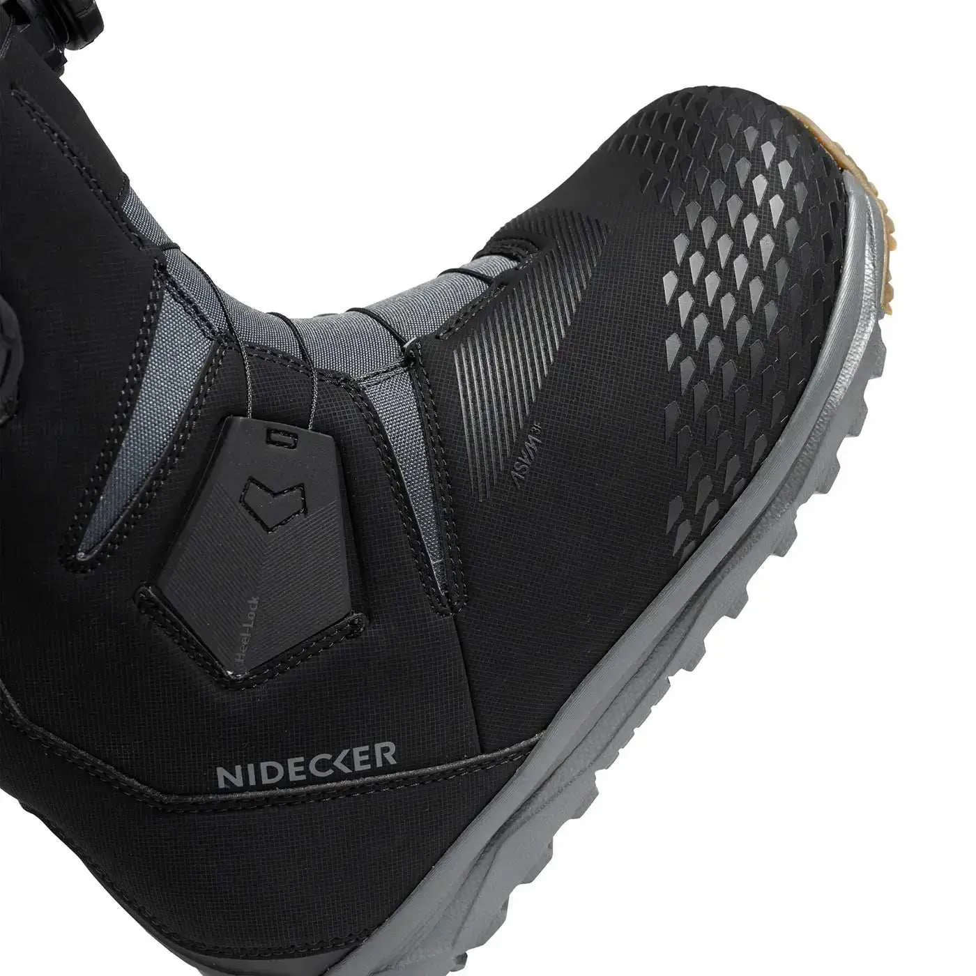 Detailed view of a black Nidecker snowboard boot with gray sole and Heellock system. The upper material has a diamond pattern.
