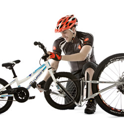Mann koppelt Kinderrad an ein Erwachsenenrad mit FollowMe Tandemkupplung, beide Räder stehen aufrecht.