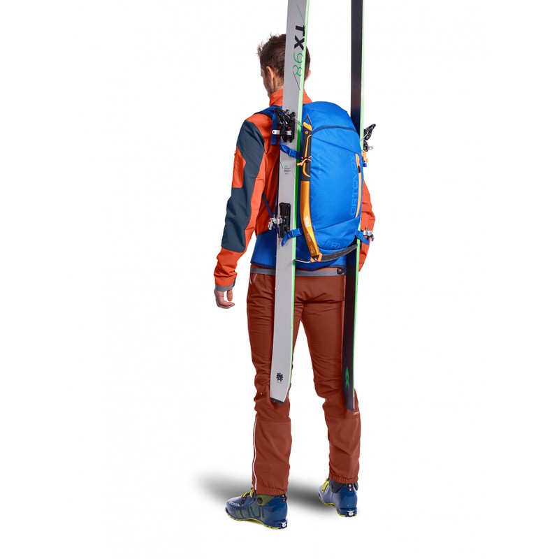 Person mit Skitourenrucksack und montierten Skiern von hinten. Blaue Ortovox Tour Rider 28 S am Rücken.