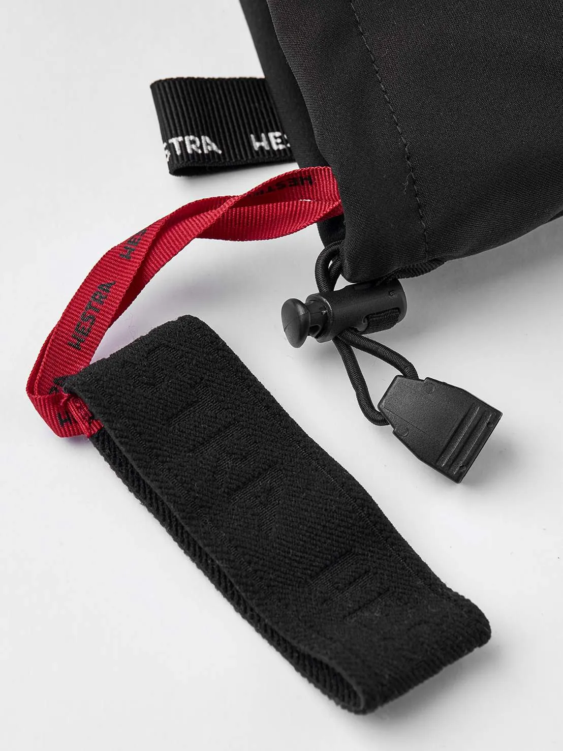 Particolare di un guanto estremo in pelle nera di Hestra Army, con coulisse e passante rosso.