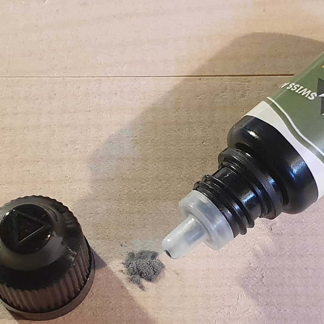 Ski Base Repair : Bouteille ouverte contenant du liquide de réparation et de la poudre pour semelles de ski sur une surface claire.