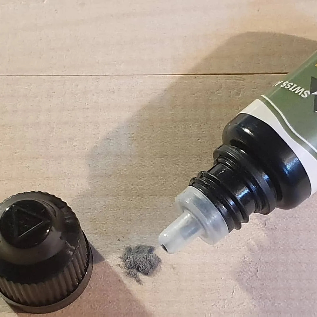 Ski Base Repair: Geöffnete Flasche mit Reparatur-Flüssigkeit und Ski Belagspulver auf hellem Untergrund.