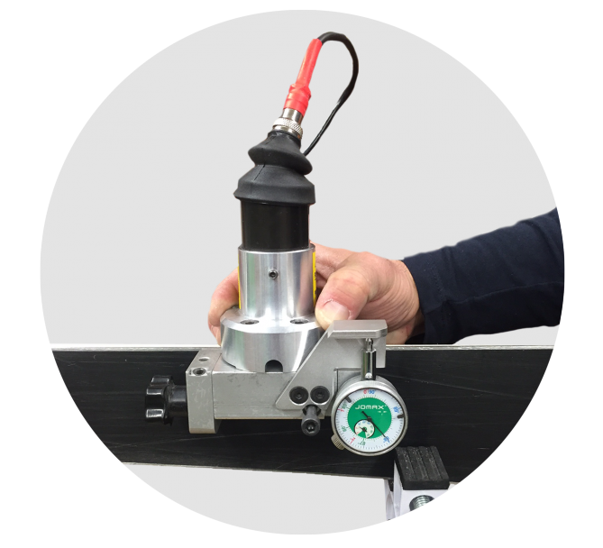 Kantenschleifmaschine in Benutzung an einem Ski, mit Hand und rotem Kabel. Anzeigeinstrument sichtbar.
