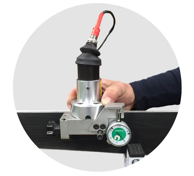 Edge grinding machine in use on a ski, with hand and red cable. Display instrument visible.