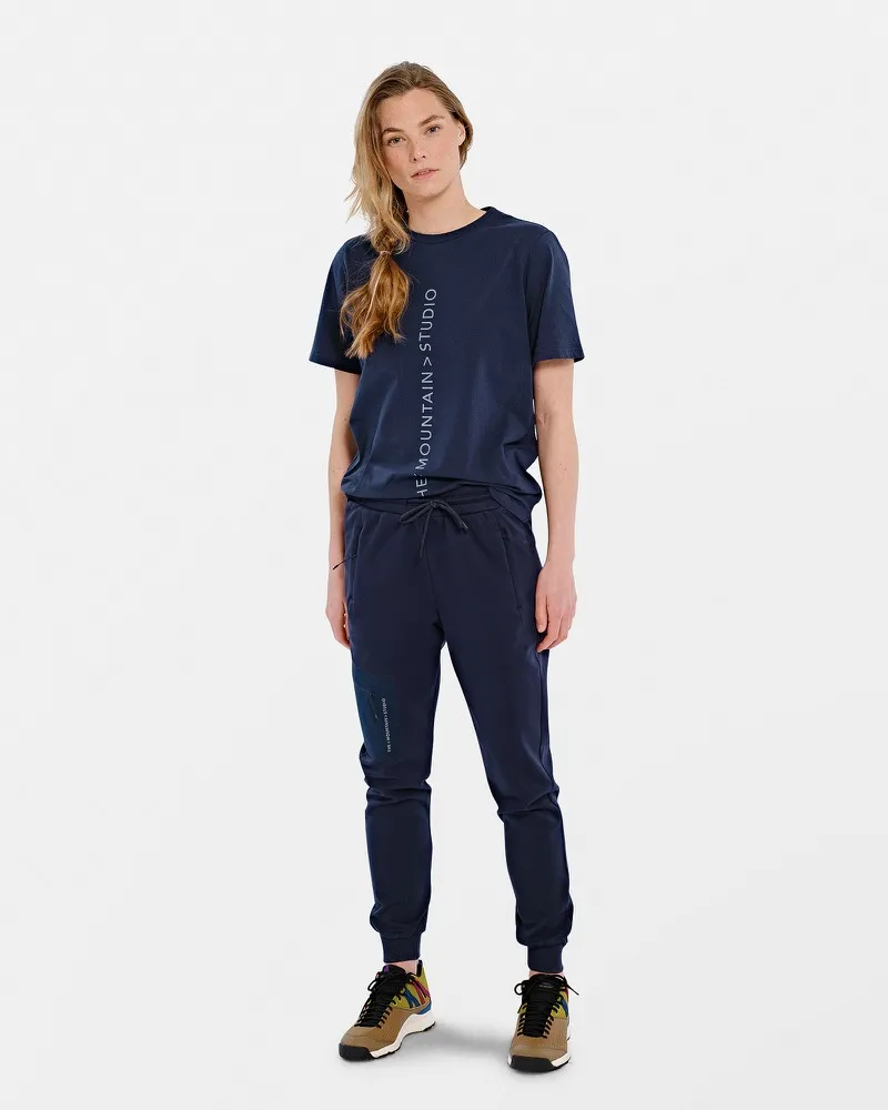 Person in navy blue T-shirt with vertical logo and matching pants.