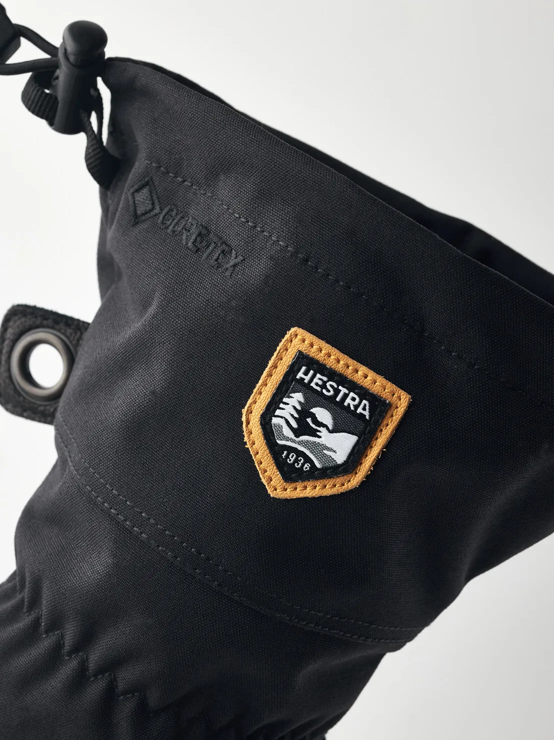 Vue détaillée d'un gant noir Hestra avec Gore-Tex et un patch logo Hestra avec l'inscription "1936".