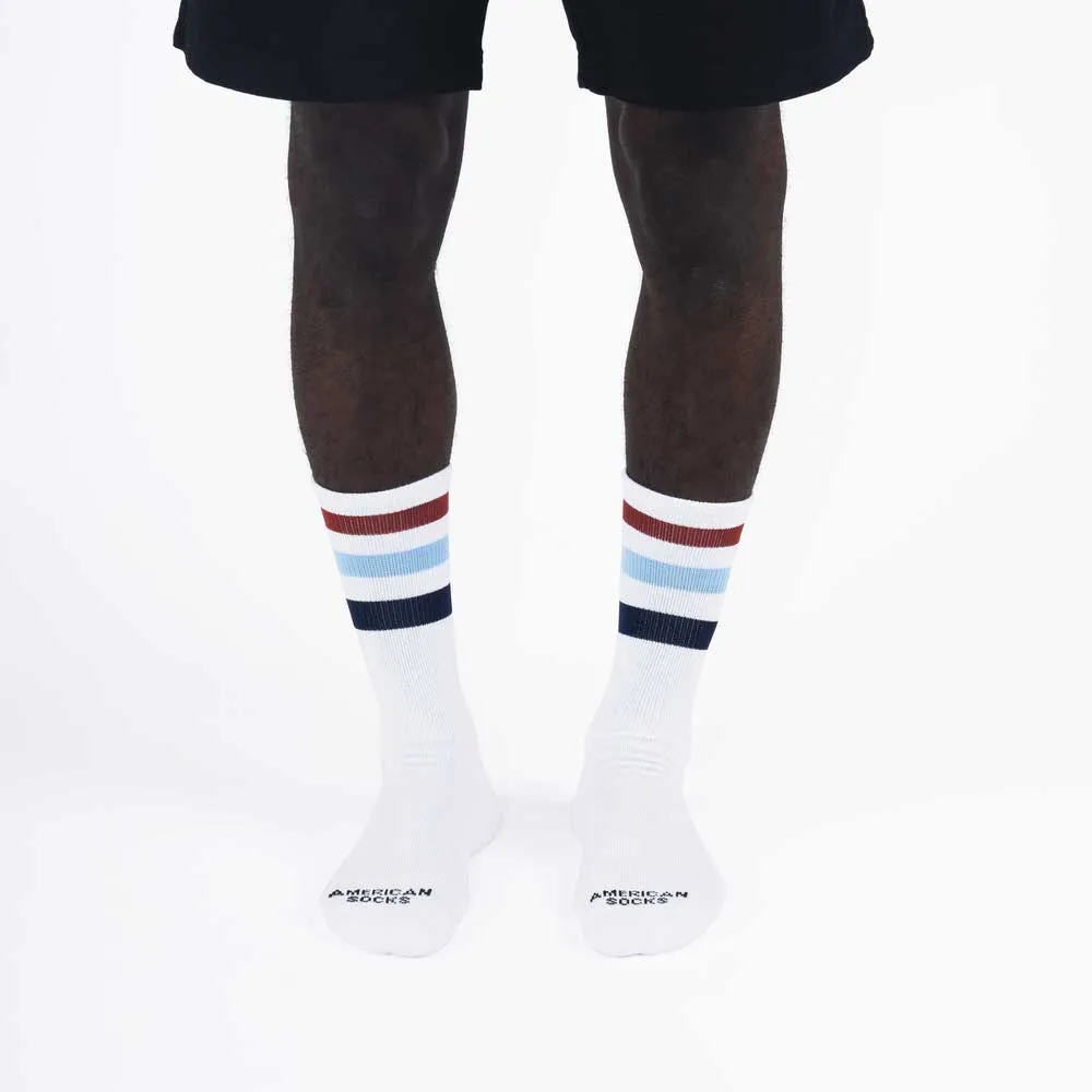 Legs with white mid high socks, colored stripes (brown, light blue, blue) on the upper edge of the sock.