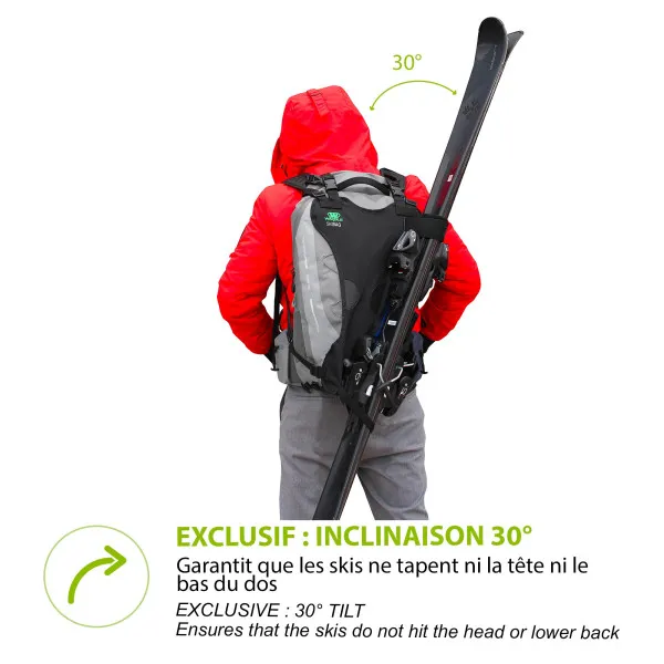 Person with red jacket wears skis attached to backpack, the skis are at a 30 degree angle.
