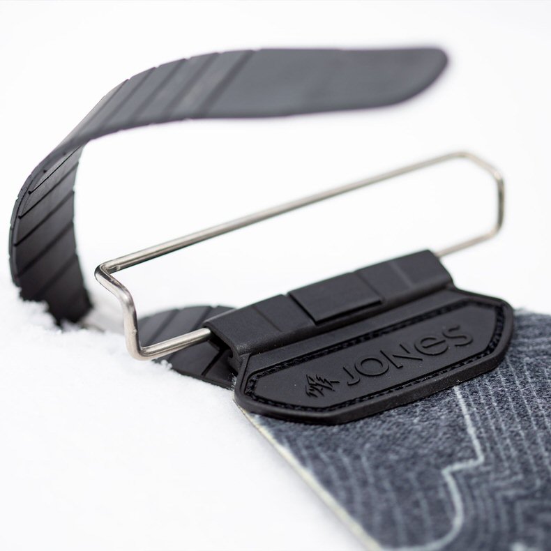 Detailaufnahme von Jones Nomad PRO Splitboard Fellbefestigung im Schnee. Der Quick Tension Tail Clip ist sichtbar.