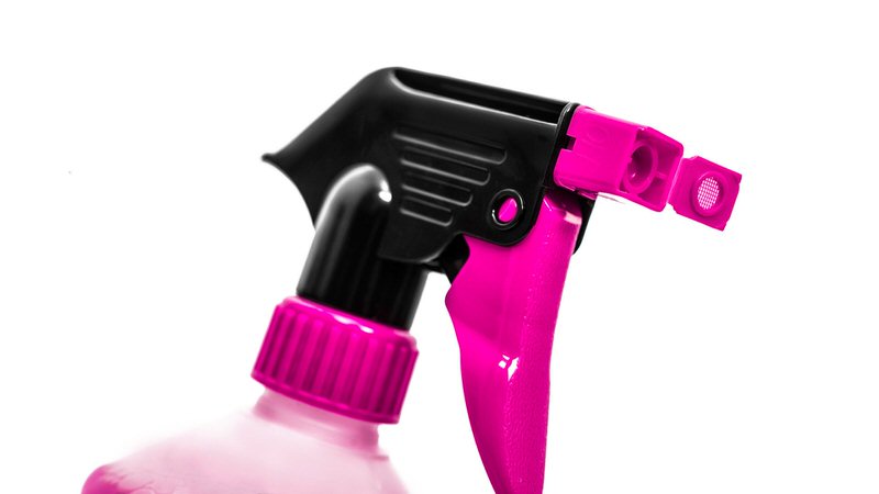 Gros plan : tête de pulvérisation rose et noire d'un flacon de nettoyage sur fond blanc.