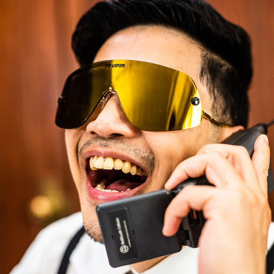 Mann mit goldener Limousine Sonnenbrille telefoniert lachend mit Handy.
