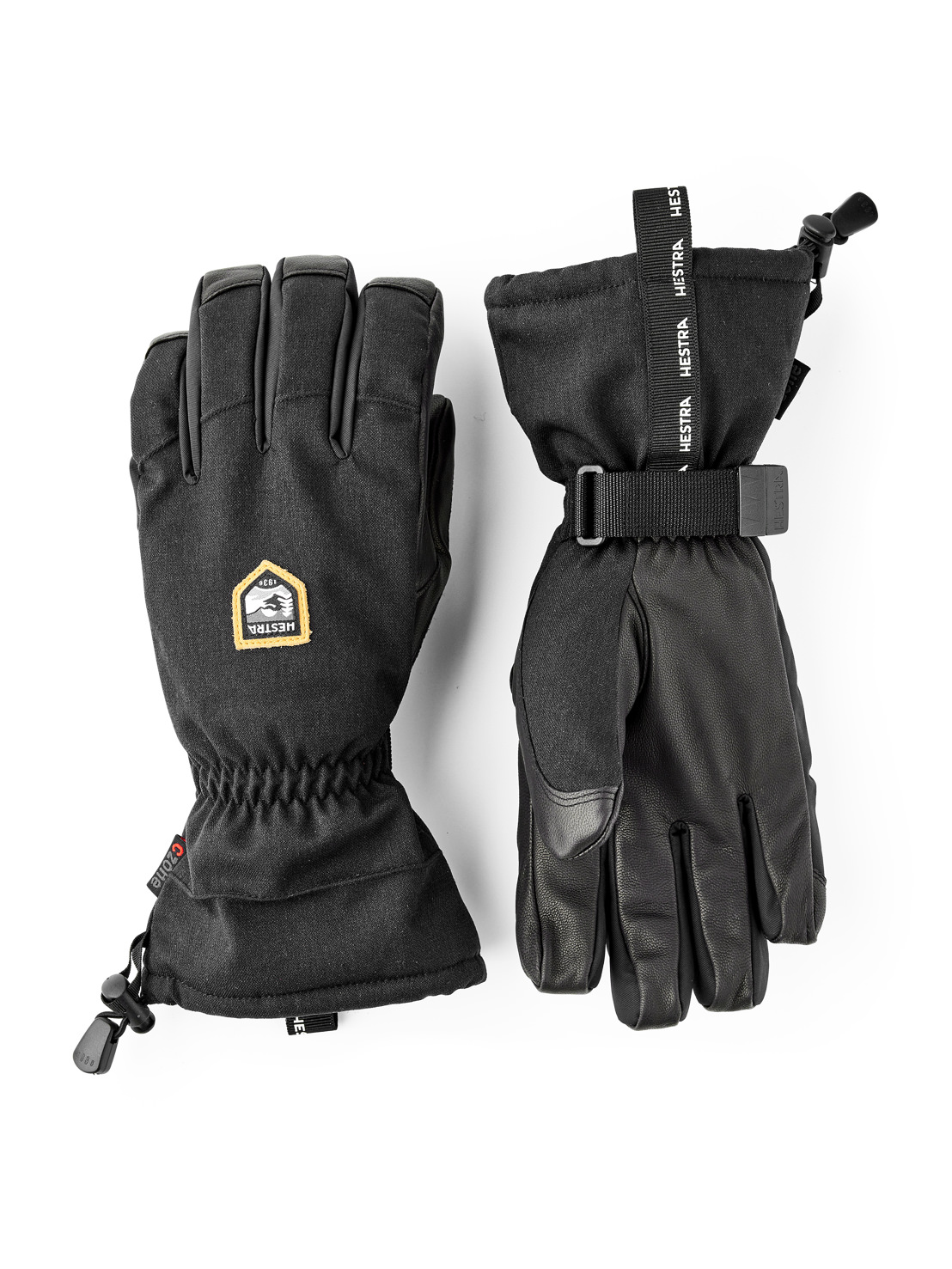 Zwei schwarze Hestra-Handschuhe, einer mit Stoffstulpe und Kordelzug, der andere mit Lederhandfläche und Gurtband.