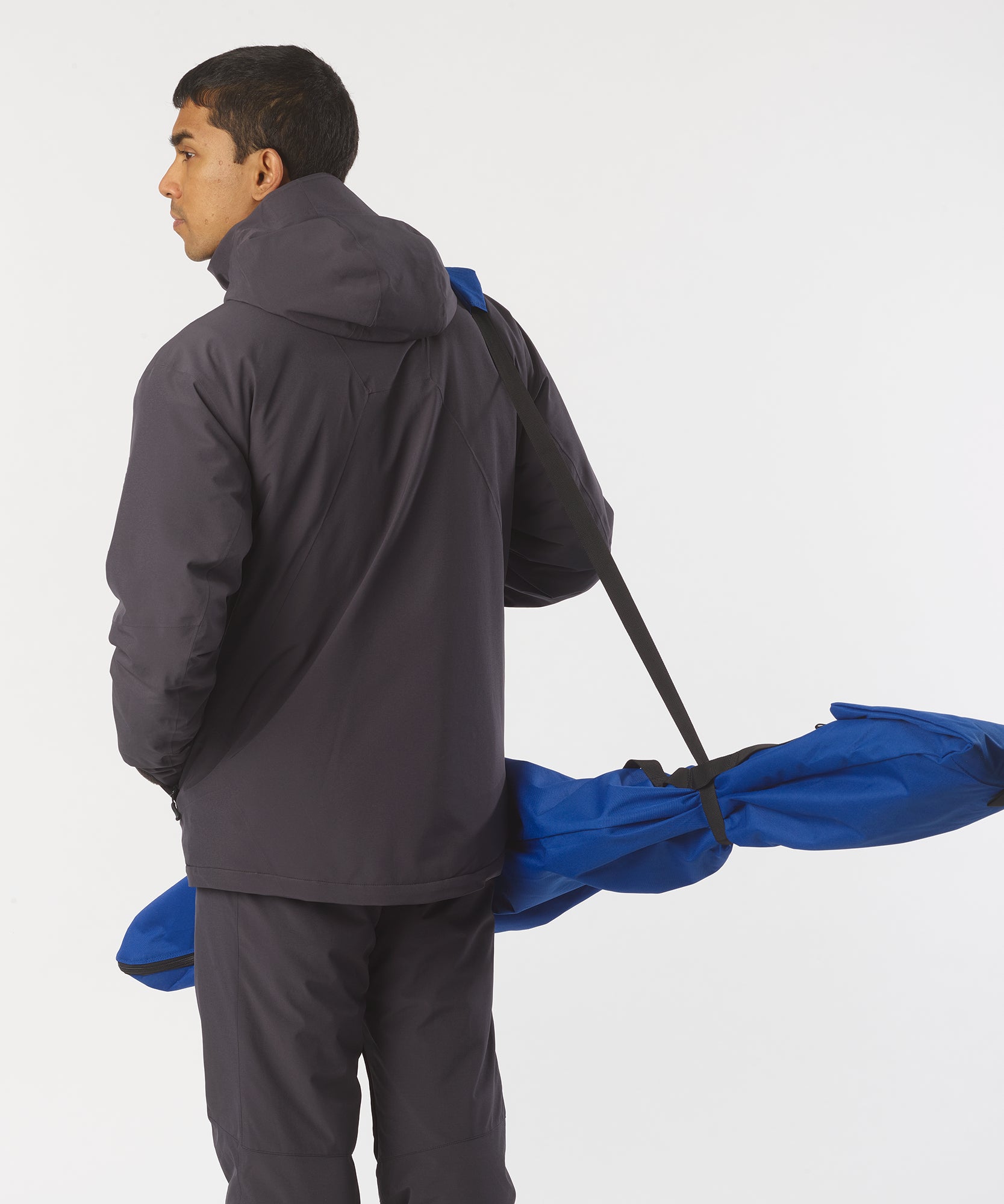 Homme portant un sac de ski bleu Salomon sur l'épaule ; vue latérale.