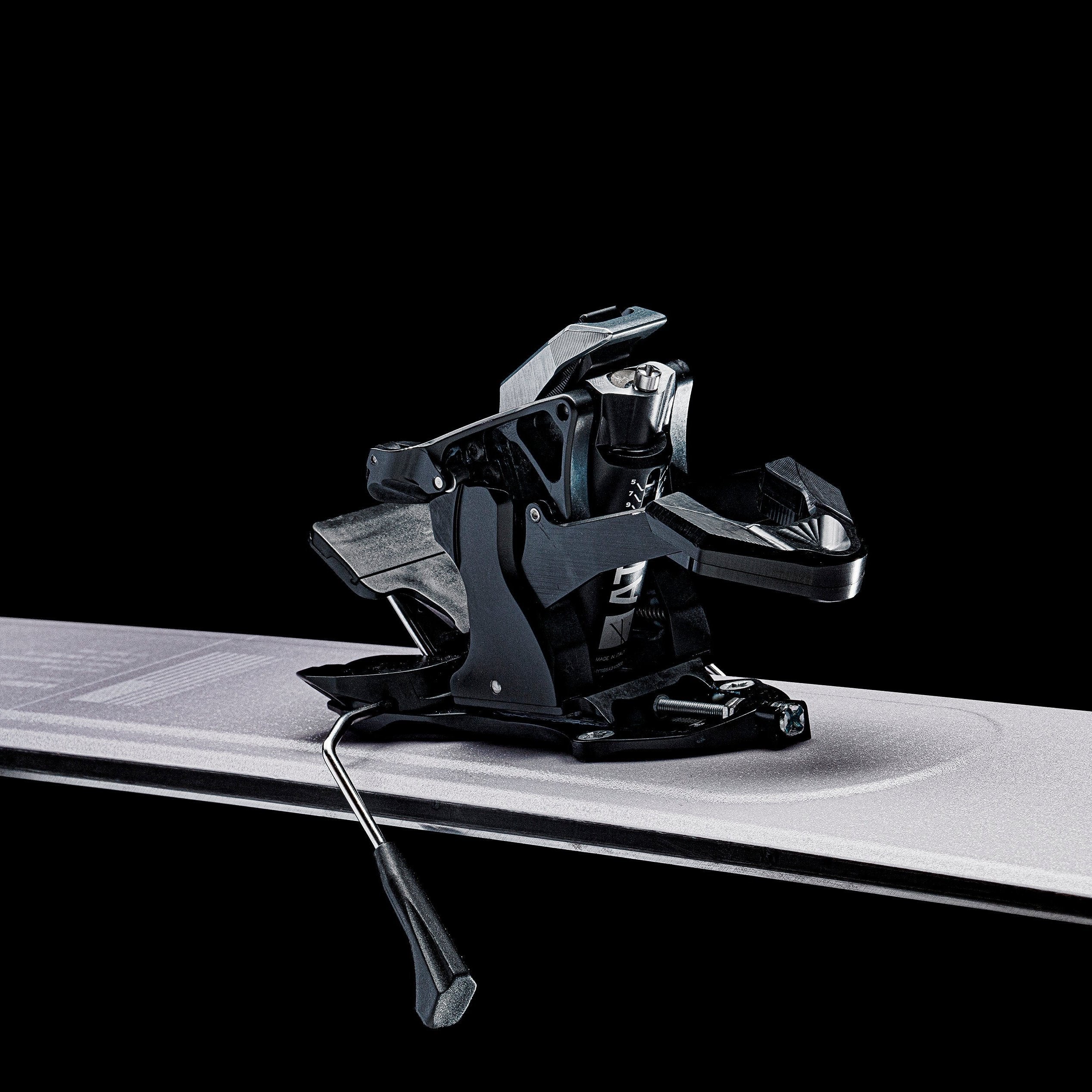 Primo piano di un attacco da sci nero su uno sci su sfondo nero.