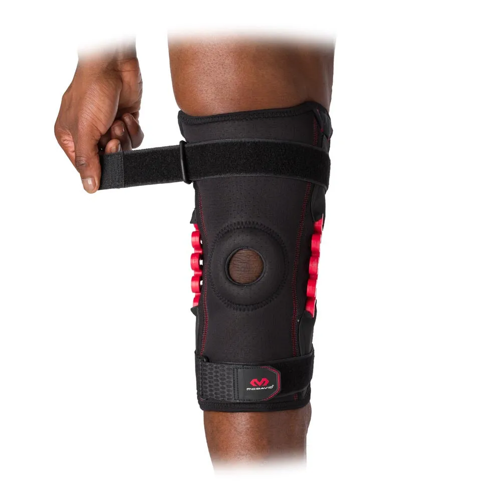 One leg with McDavid NRG Knee Brace 30630 on, the brace is black with red accents and is fastened with Velcro.
