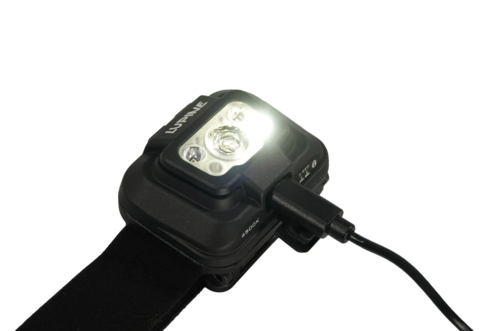 Lampe frontale Penta 4500k noire, sur le câble de recharge, avec lumière vive allumée.