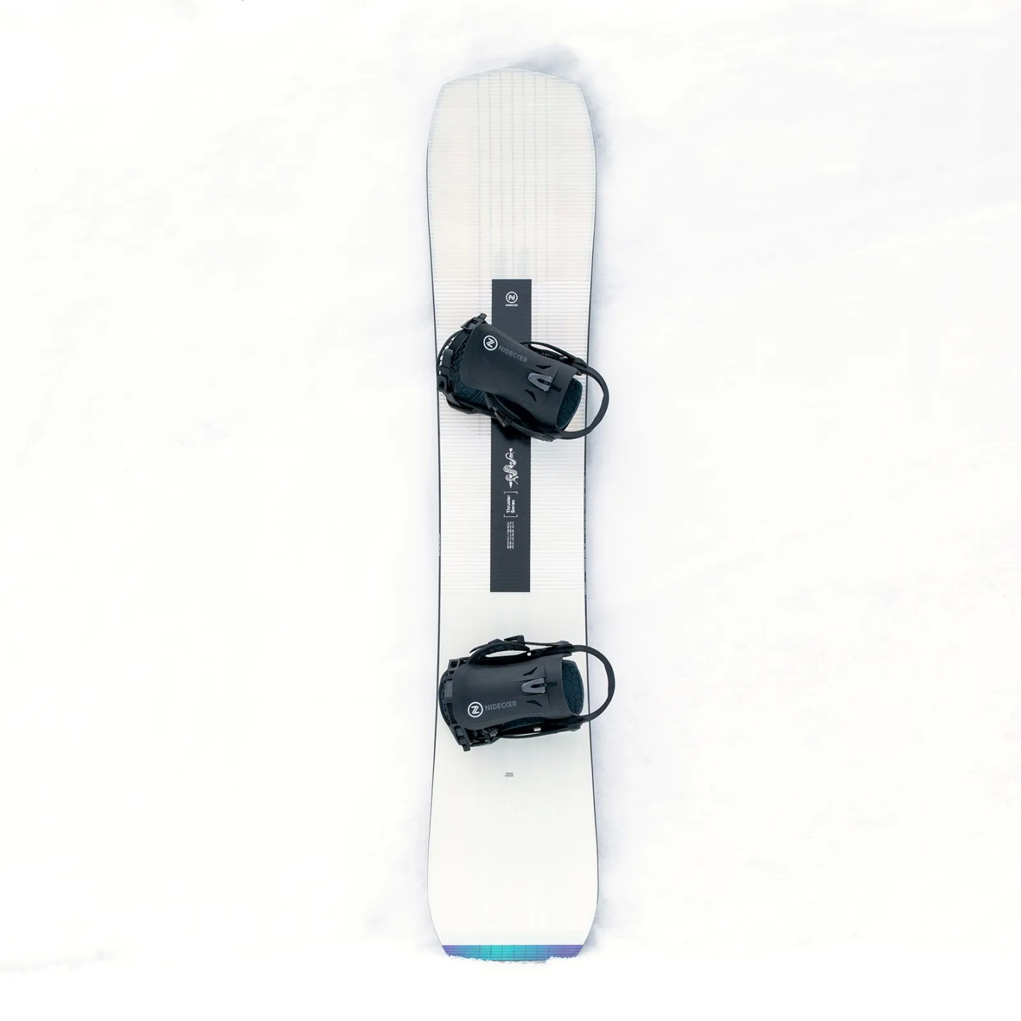 Nidecker Thruster Snowboard Draufsicht des Nidecker Thruster Snowboards im Schnee. Das Brett ist weiß mit schwarzen Bindungen und Grafiken.