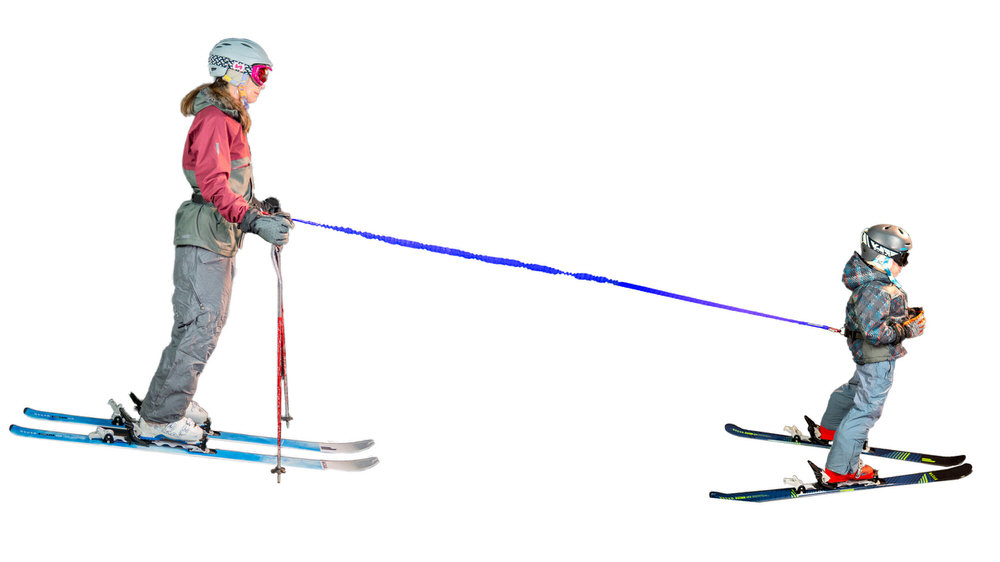 Skifahrende Frau und Kind durch blaues Seil verbunden. Frau trägt Tow-Whee Hüftgurt und zieht Kind auf Skiern.