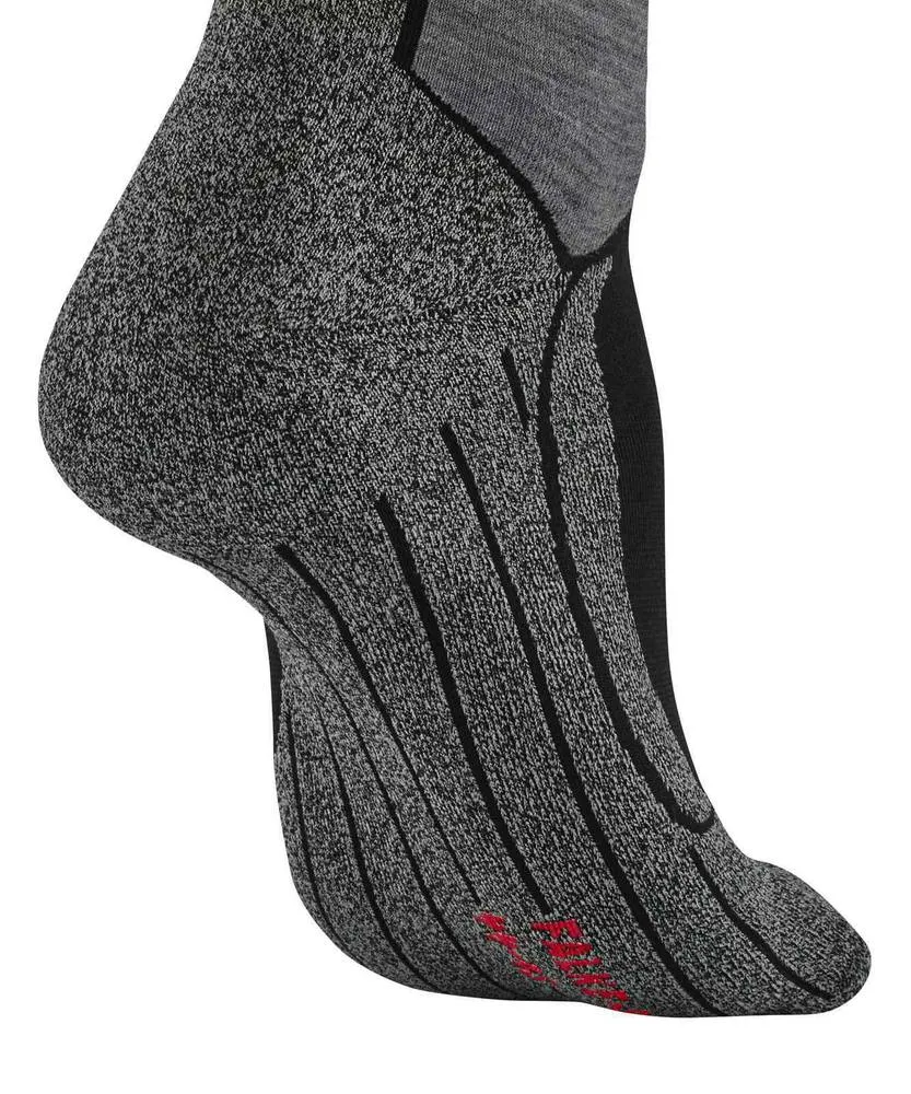 Ein menschlicher Fuß trägt einen sportlichen Socke in Grau-Schwarz auf weißem Hintergrund. Gesprenkeltes Grau-Weiß-Strickmuster, schwarze Zonen an Fußgewölbe und Zehen, dünne vertikale Linien sowie rote Schrift auf der Sohle nahe den Zehen.