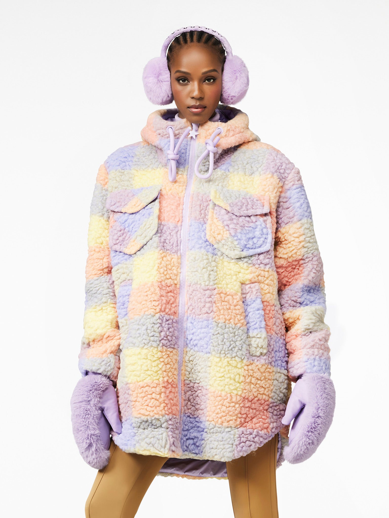 Model trägt die karierte, flauschige Chad Jacket in Pastellfarben mit passenden Ohrenwärmern und Handschuhen.