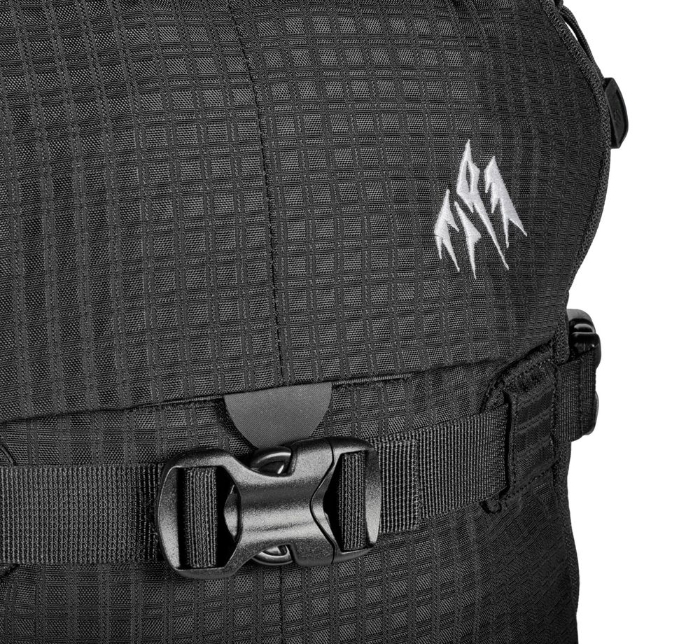 Jones DSCNT RAS Rucksack Detailaufnahme des Jones DSCNT RAS Rucksacks: Schwarzes, strukturiertes Material mit Schnalle und weißem Logo.