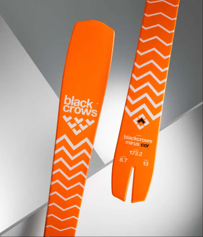 Close-up of two orange Black Crows skis with a white zigzag pattern and the Marker logo.