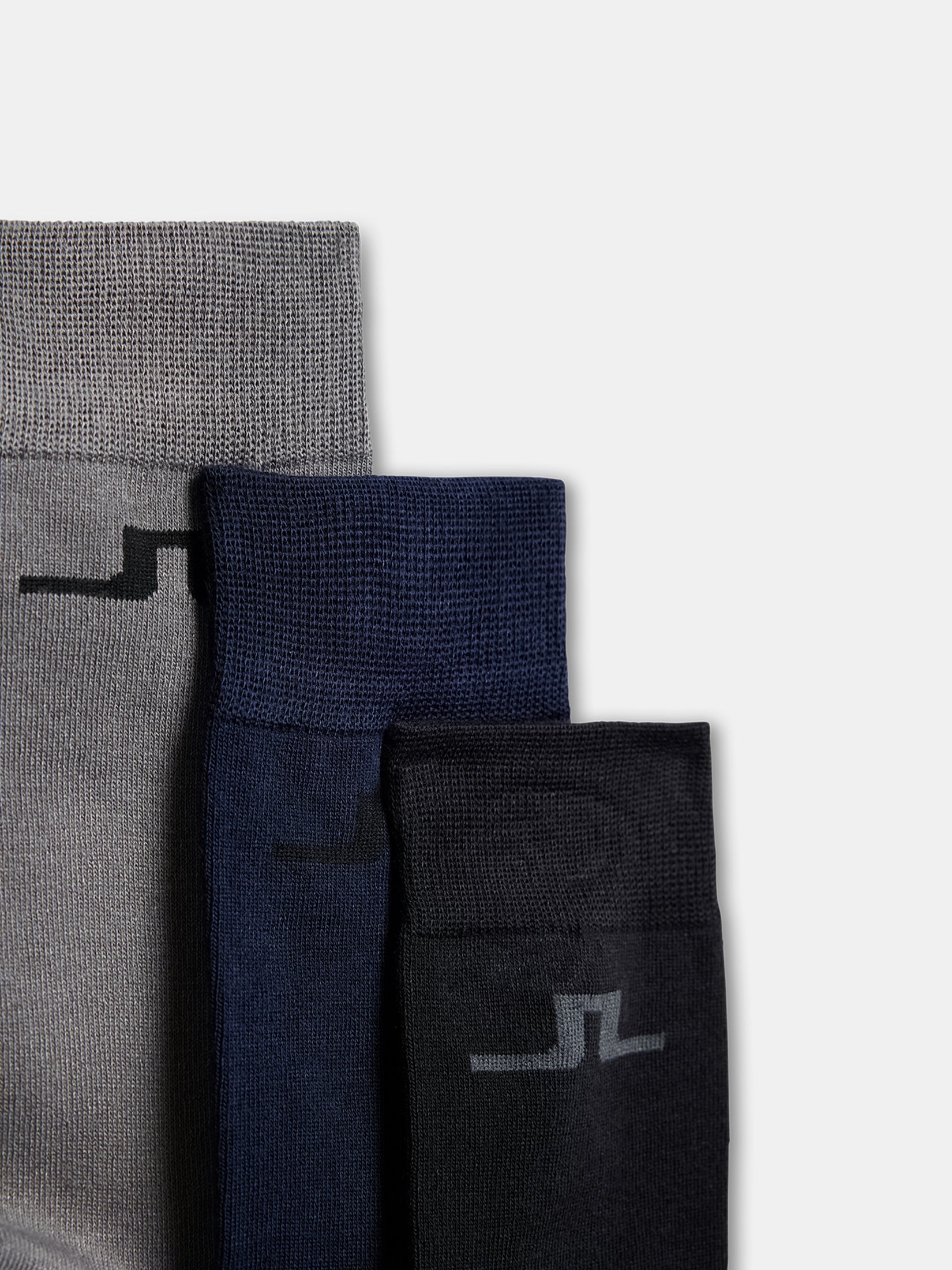Trois chaussettes J.Lindeberg en pack de 3 en gris, bleu foncé et noir, avec le logo Bridge sur la tige.