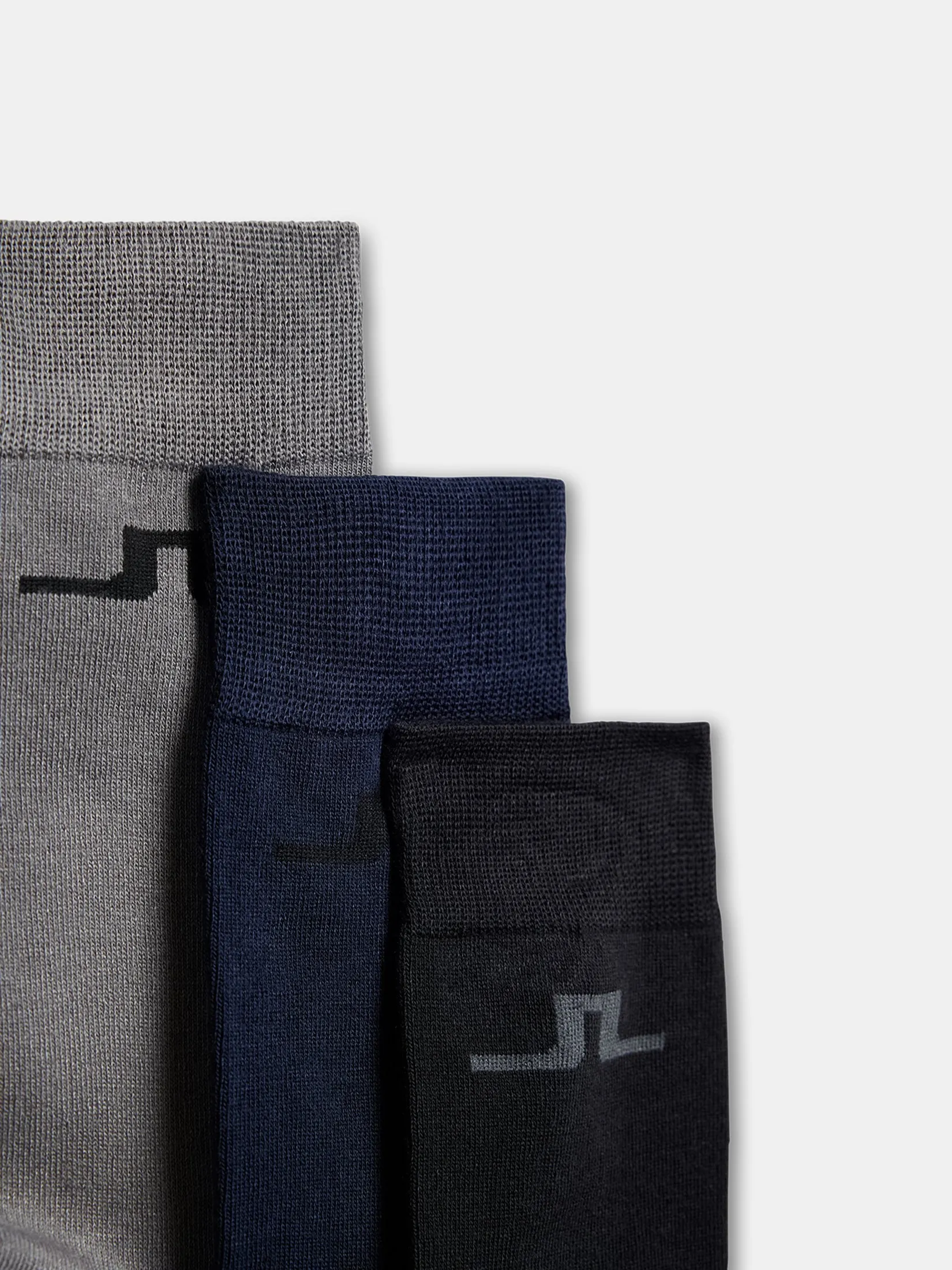 Trois chaussettes J.Lindeberg en pack de 3 en gris, bleu foncé et noir, avec le logo Bridge sur la tige.