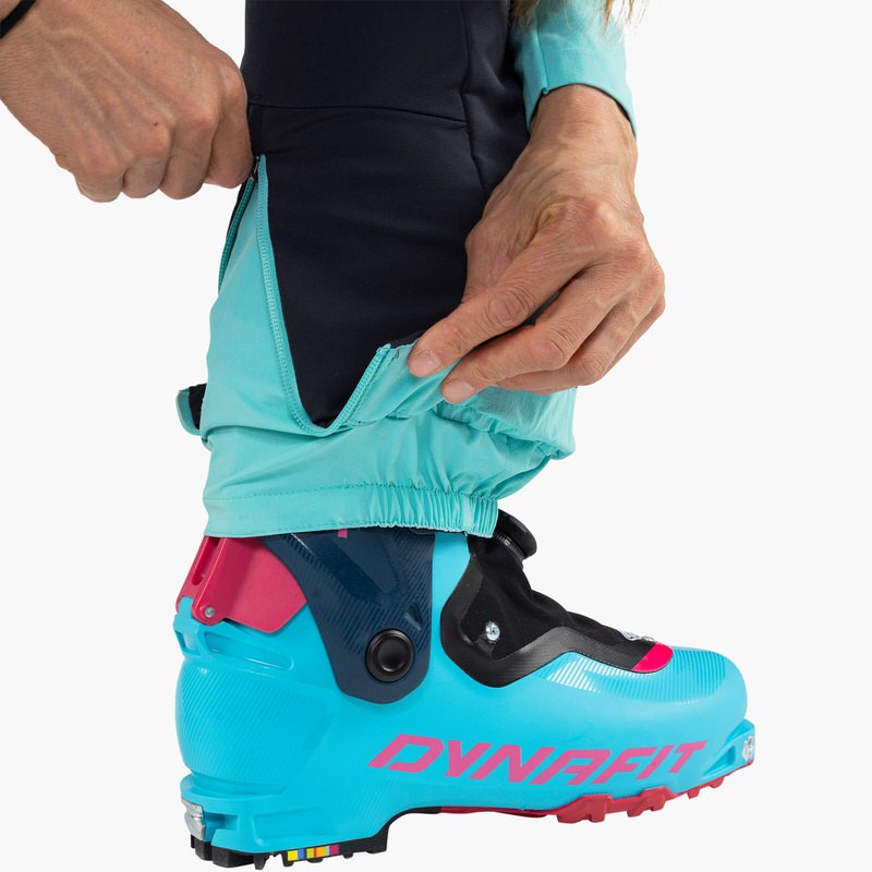 Gros plan : pantalon bleu pour femme Dynafit TLT Touring DST, fermeture éclair sur la jambe ouverte sur la chaussure de ski.