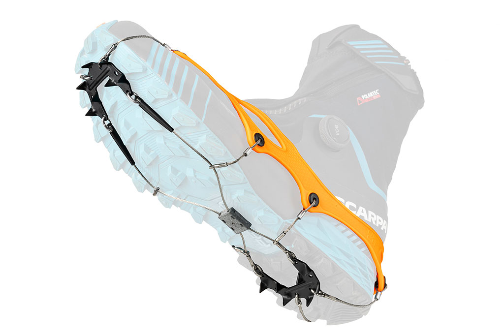 Nahaufnahme einer Trail 2.4 Orange Schuhkralle am Schuh. Die Kralle hat Stahlspitzen und ein oranges Elastomer-Band.