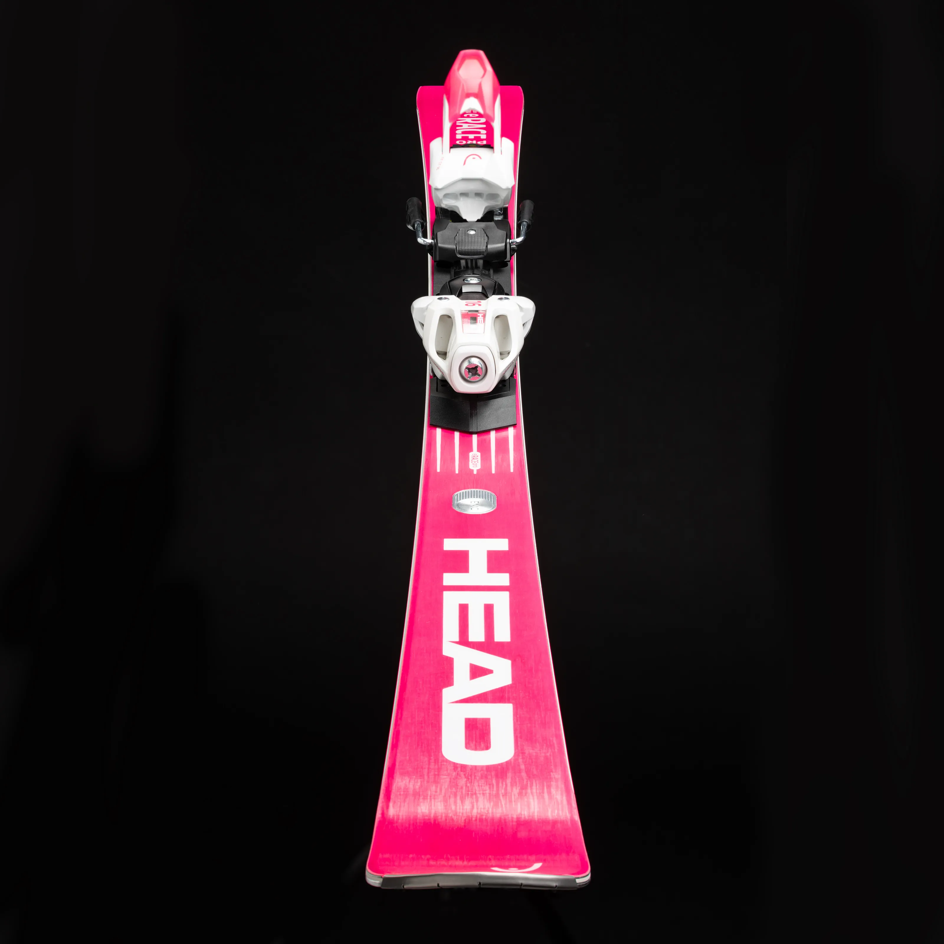 Pinkfarbener Head WC Rebels e-Race Pro Ski, Frontalansicht, mit weißer Bindung, auf schwarzem Hintergrund.