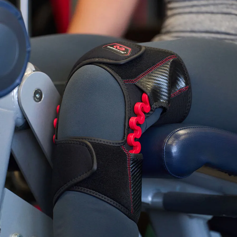 Close-up of the McDavid NRG Knee Over Wrap 30590 on the knee. The support is black with red details and stabilizes the knee joint.