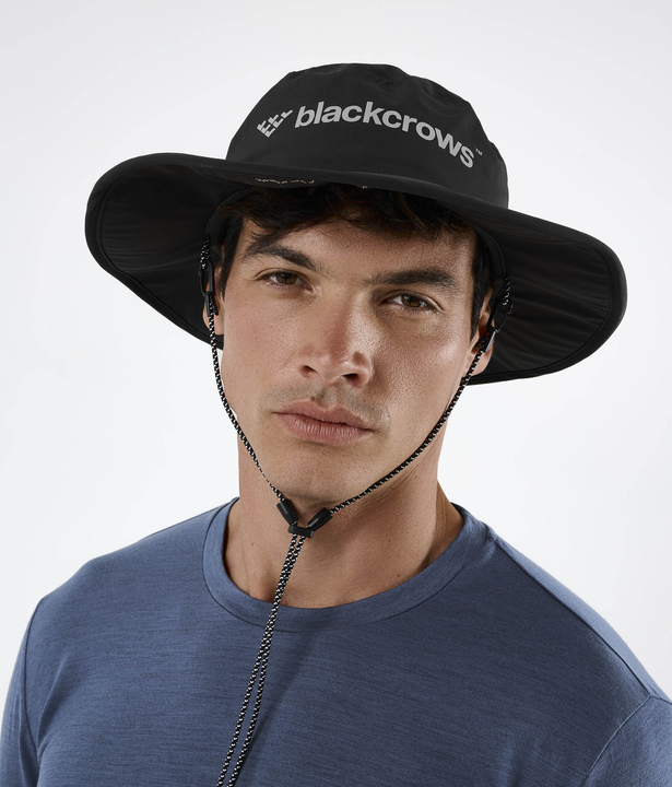 Ein Mann trägt einen schwarzen Black Crows Boonus Hut mit breiter Krempe und Kordel.