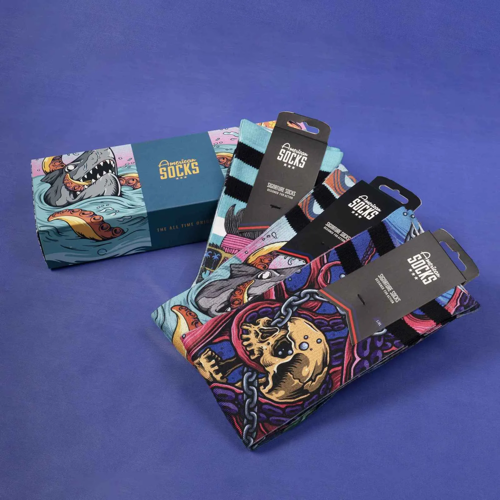 Geschenkbox mit Seacreatures Socken: Eine Box mit Hai-Motiv und drei Paar Socken mit Oktopus, Hai und Totenkopf Design.