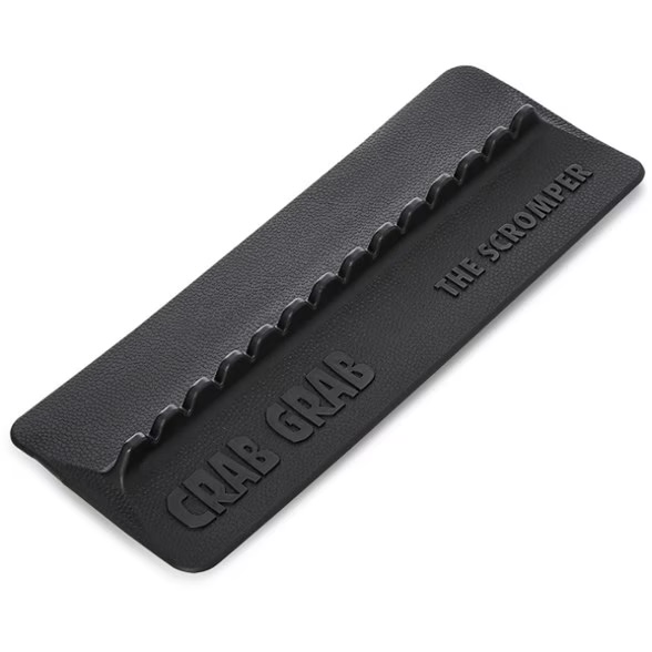 Schwarzes, rechteckiges Crab Grab Scromper Stomp Pad mit strukturierter Oberfläche. An einer Längsseite sieben erhabene, wellenförmige Zacken zum Reinigen von Schuhsohlen. Prägungen: „CRAB GRAB“, „THE SCROMPER“.