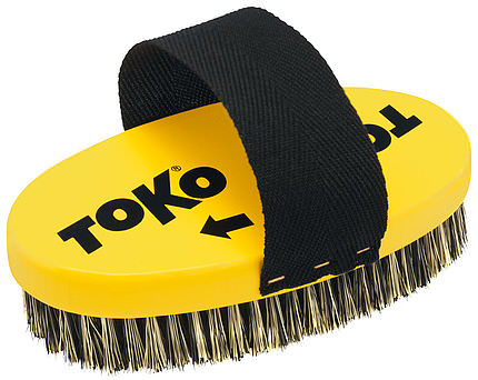 Gelbe, ovale Stahlbürste mit schwarzem Haltegurt und Stahlborsten. "TOKO"-Logo auf dem gelben Griff.