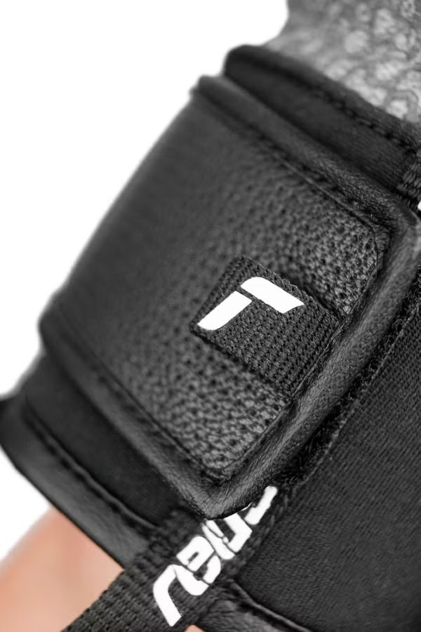 Reusch Marco Odermatt Handschuh Detailaufnahme des Handgelenks eines schwarzen Reusch Marco Odermatt Handschuhs mit weißem Logo.