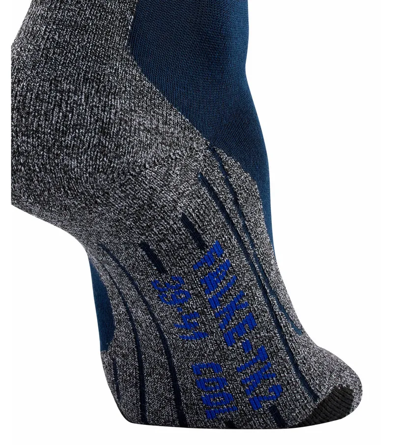 Gros plan sur une chaussette de trekking grise avec un talon bleu et le logo Falke bleu.