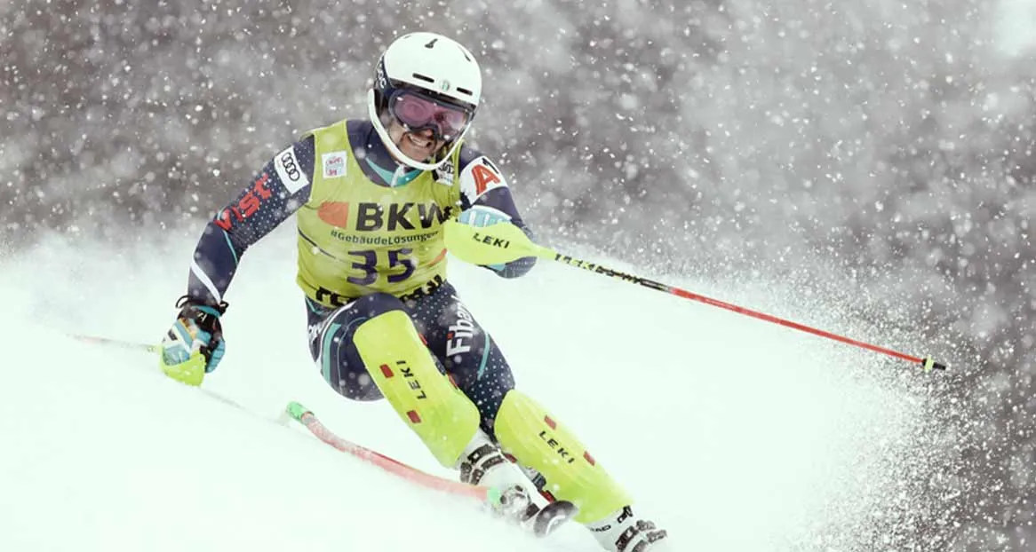 Ski racer in action, with helmet and goggles, number 35, in snowfall on the piste.