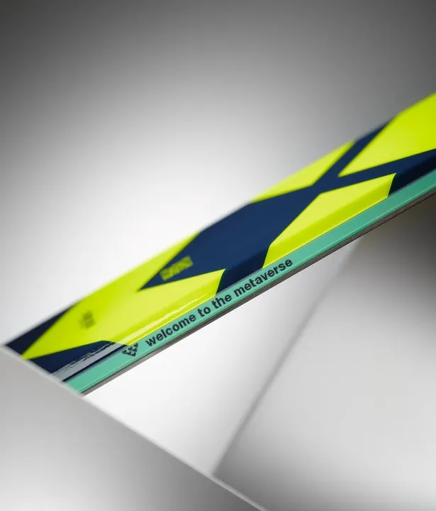Vue détaillée du ski Black Crows Atris avec un motif jaune et bleu et l'inscription "Welcome to the Metaverse".