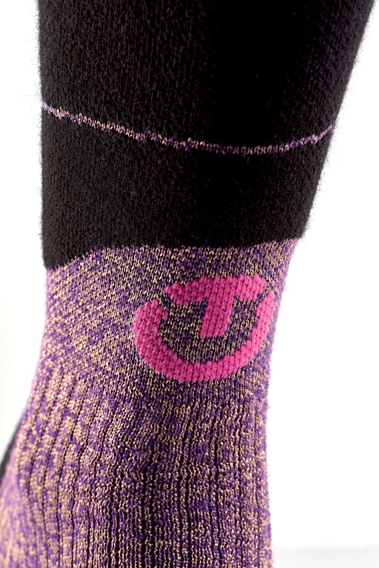 Merino Ski Socke Damen Detailaufnahme: Ski Merino Reflector Women Socke mit pinkem Logo auf lila-goldenem Grund, oberer Teil schwarz.