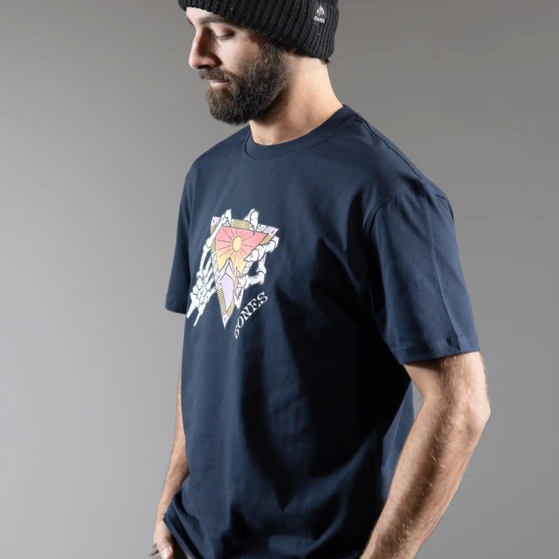 Homme portant un T-shirt graphique Homme avec casquette, portant un T-shirt bleu foncé avec une impression graphique : soleil, triangle et os de la main.